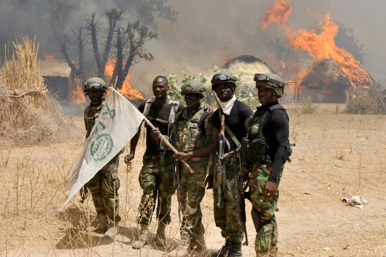 Soldiers with flag near burning huts.